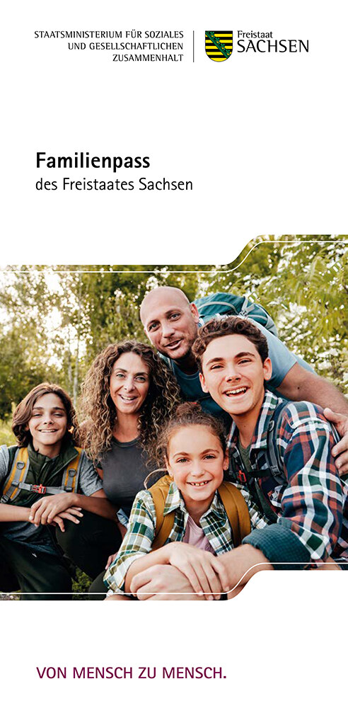 Ein junges Mädchen lacht herzlich in die Kamera. Um sie herum sitzt ihre Familie.