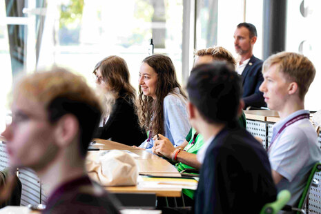 junge Menschen sitzen an Plenartischen