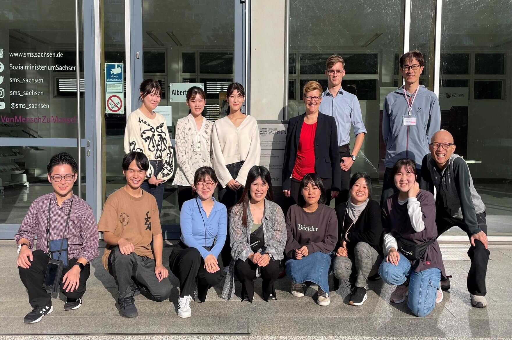 Gruppenbild japanischer junger Menschen mit der Kinder- und Jugendbeauftragten vor dem Sächsischen Sozialministerium