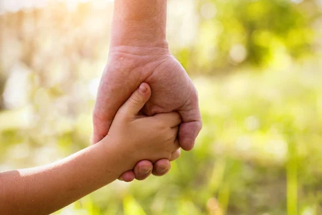 Eine Kinderhand fasst in die Hand eines Erwachsenen