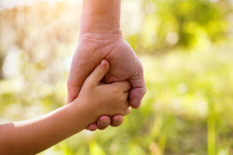 Eine Kinderhand fasst in die Hand eines Erwachsenen