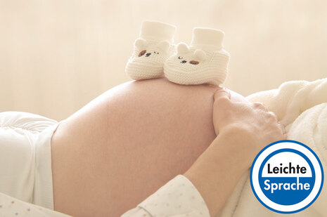 Bildausschnitt: Bauch einer Schwangeren. Darauf stehen 2 Babyschuhe. In der Ecke steht das Siegel mit der Aufschrift "Leichte Sprache"