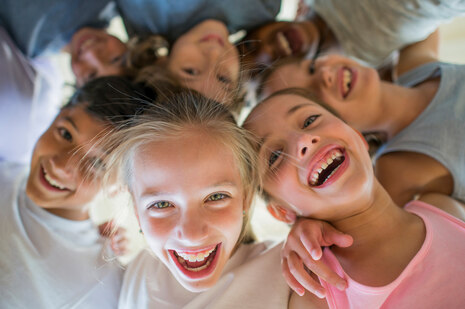 fröhliche Grundschulkinder Schulter an Schulter blicken von oben auf den Fotografen in die Kamera