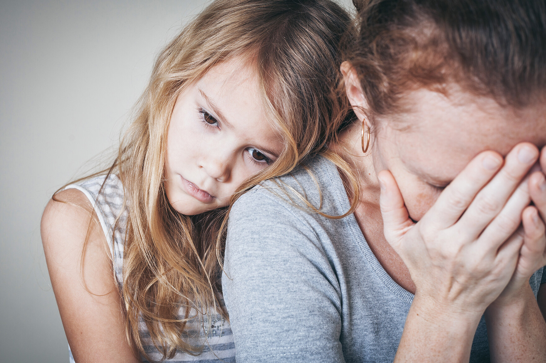 Eine Mutter hält die Hände vor das Gesicht. Die Tochter lehnt sich tröstend an ihre Schulter.