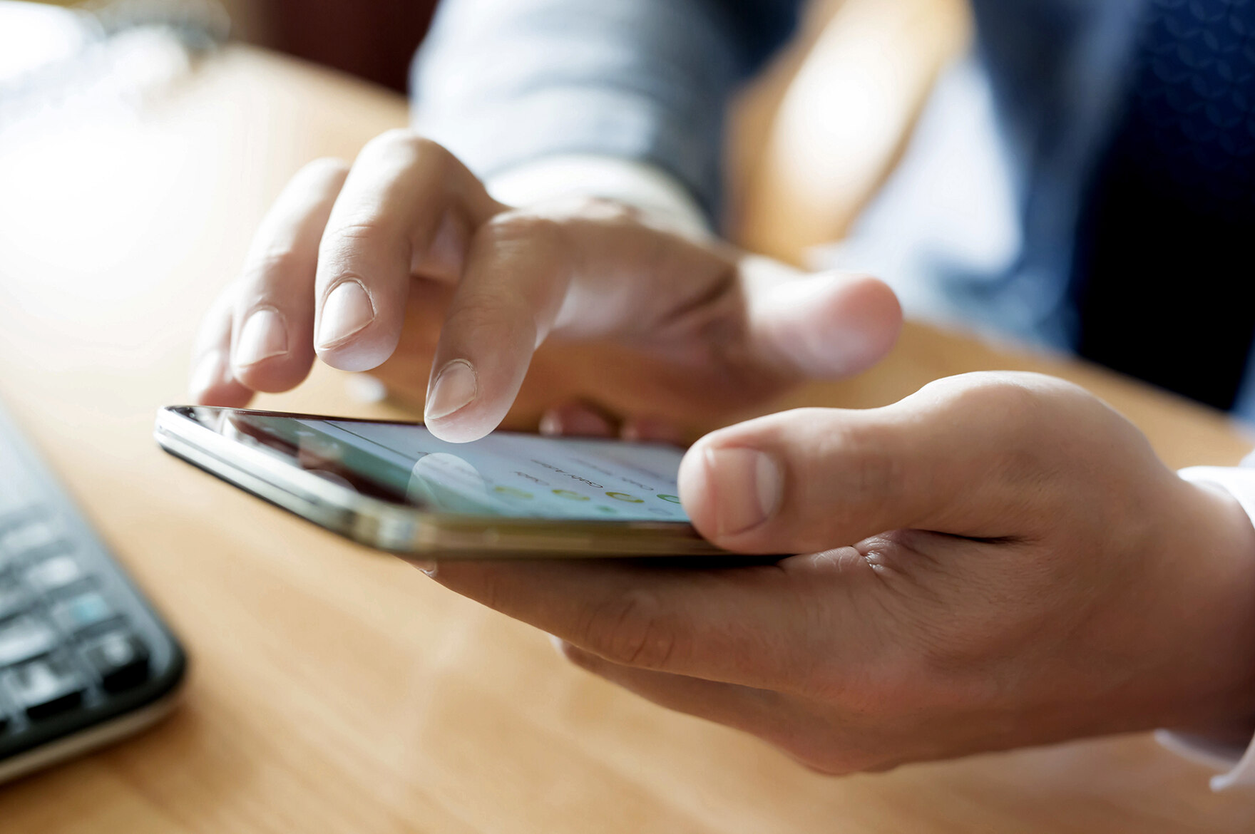 Jemand hat ein Mobiltelefon in der Hand und wählt eine Nummer