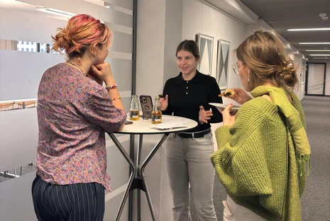 Drei Jugendliche stehen an einem Tisch und besprechen ein Thema
