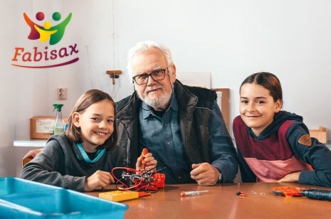 Bildmontage: Zwei Kinder sitzen an einem Tisch, der Großvater beider sitzt in der Mitte. Daneben das Logo der Datenbank bestehend aus drei farbig gestalteten Figuren und dem Schriftzug Fabisax.